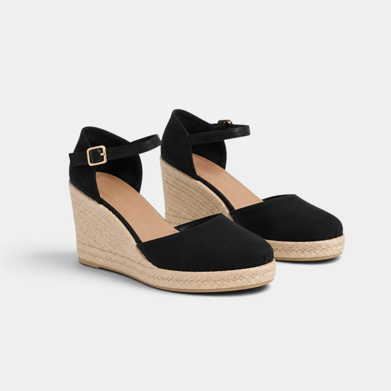 Black wedge sandals with espadrille soles on a light gray background