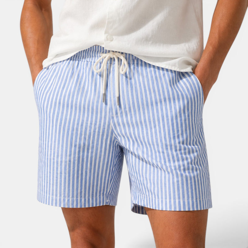 Blue and white striped shorts worn by a person on a plain background
