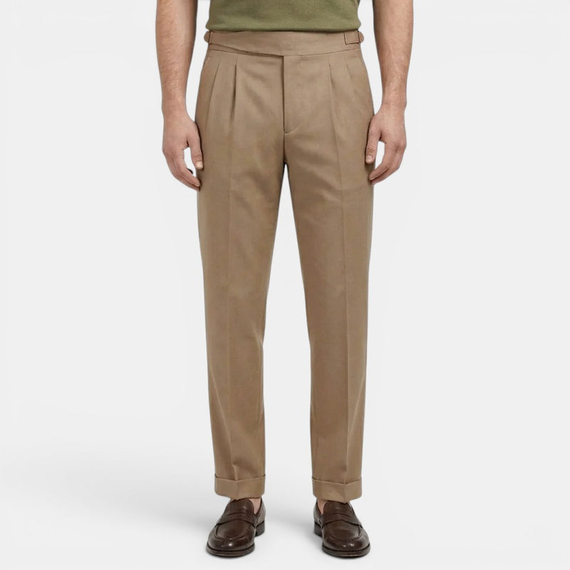 Beige pleated pants worn by a person on a white background