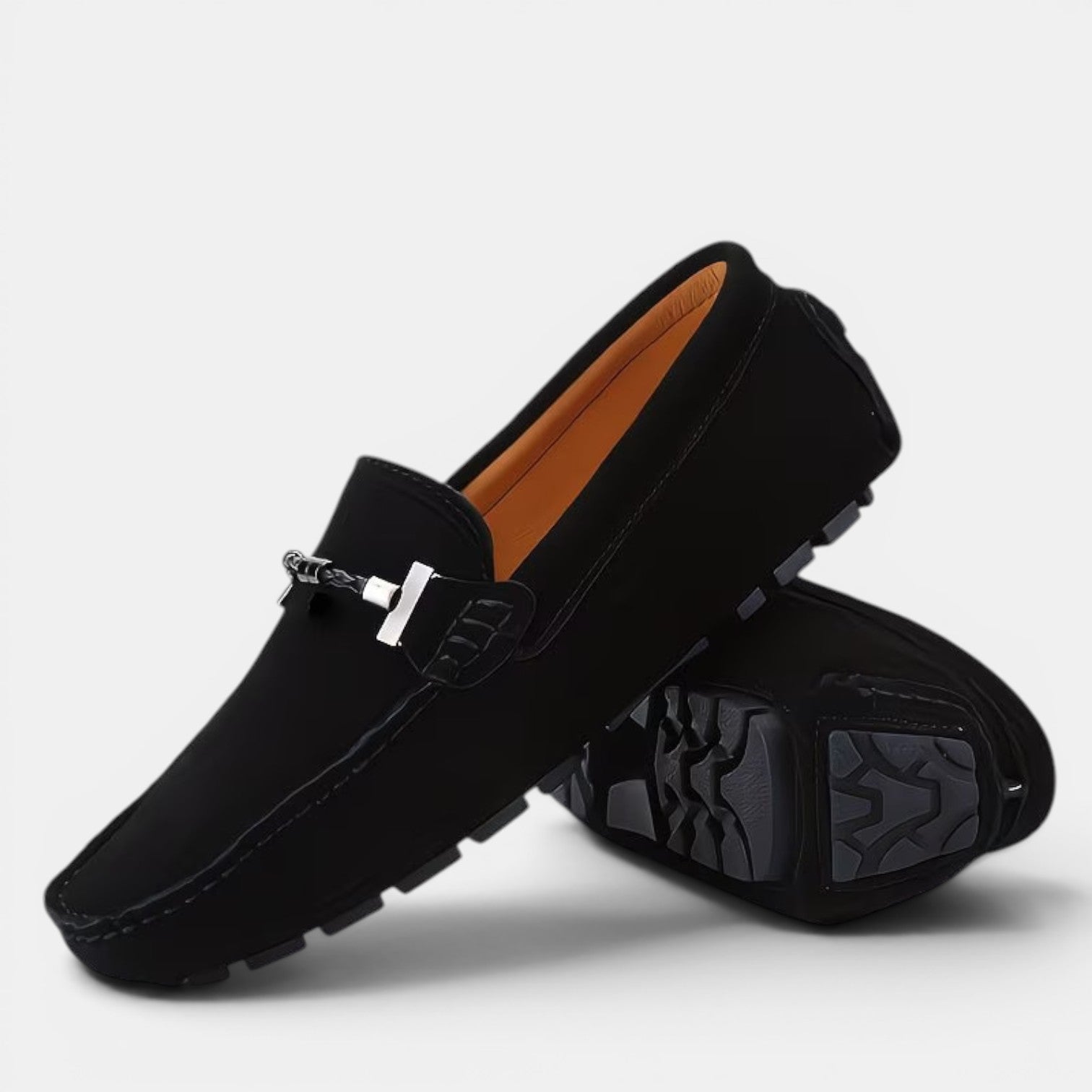 Black loafers with a silver buckle on a light gray background