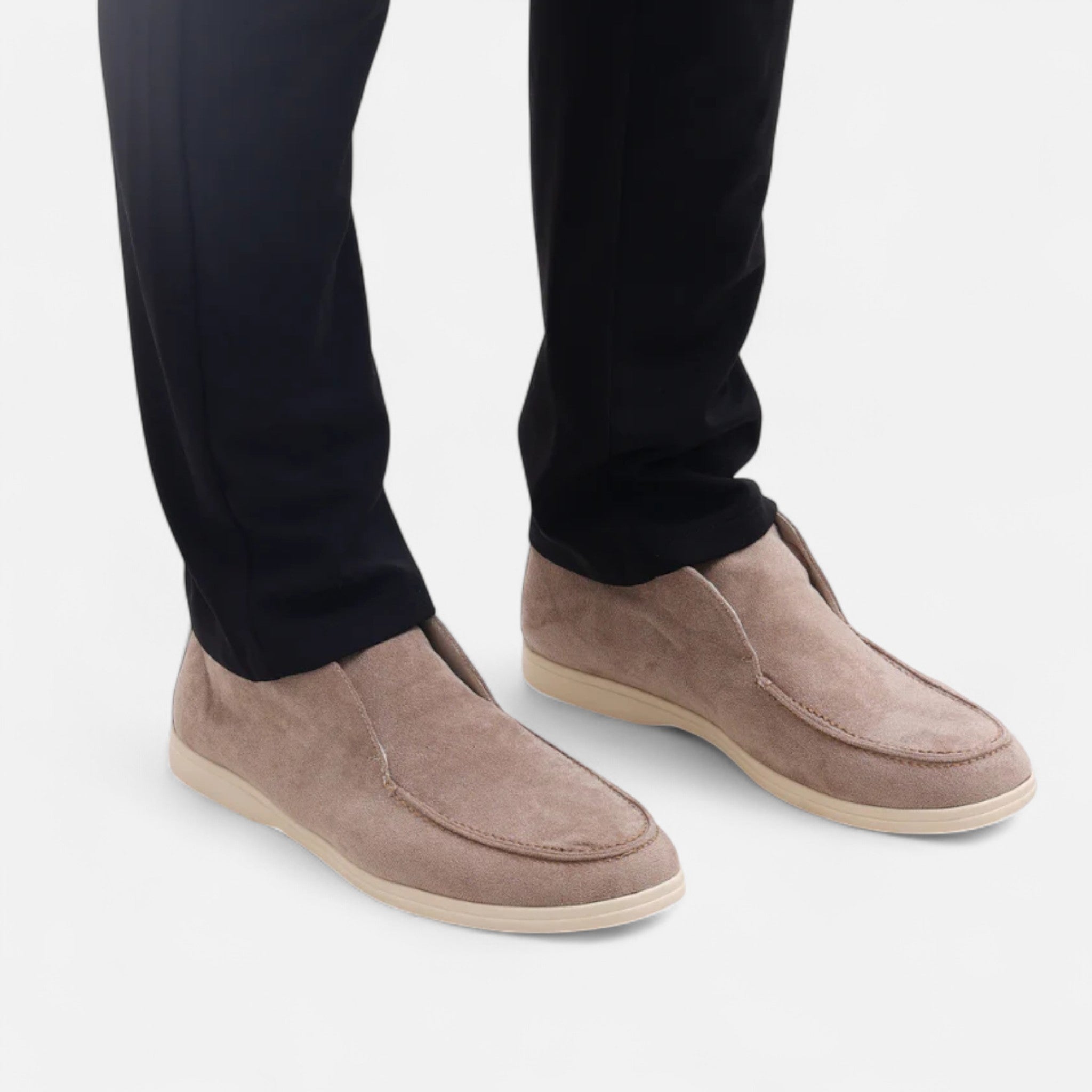 Brown suede shoes worn with black pants on a light gray background