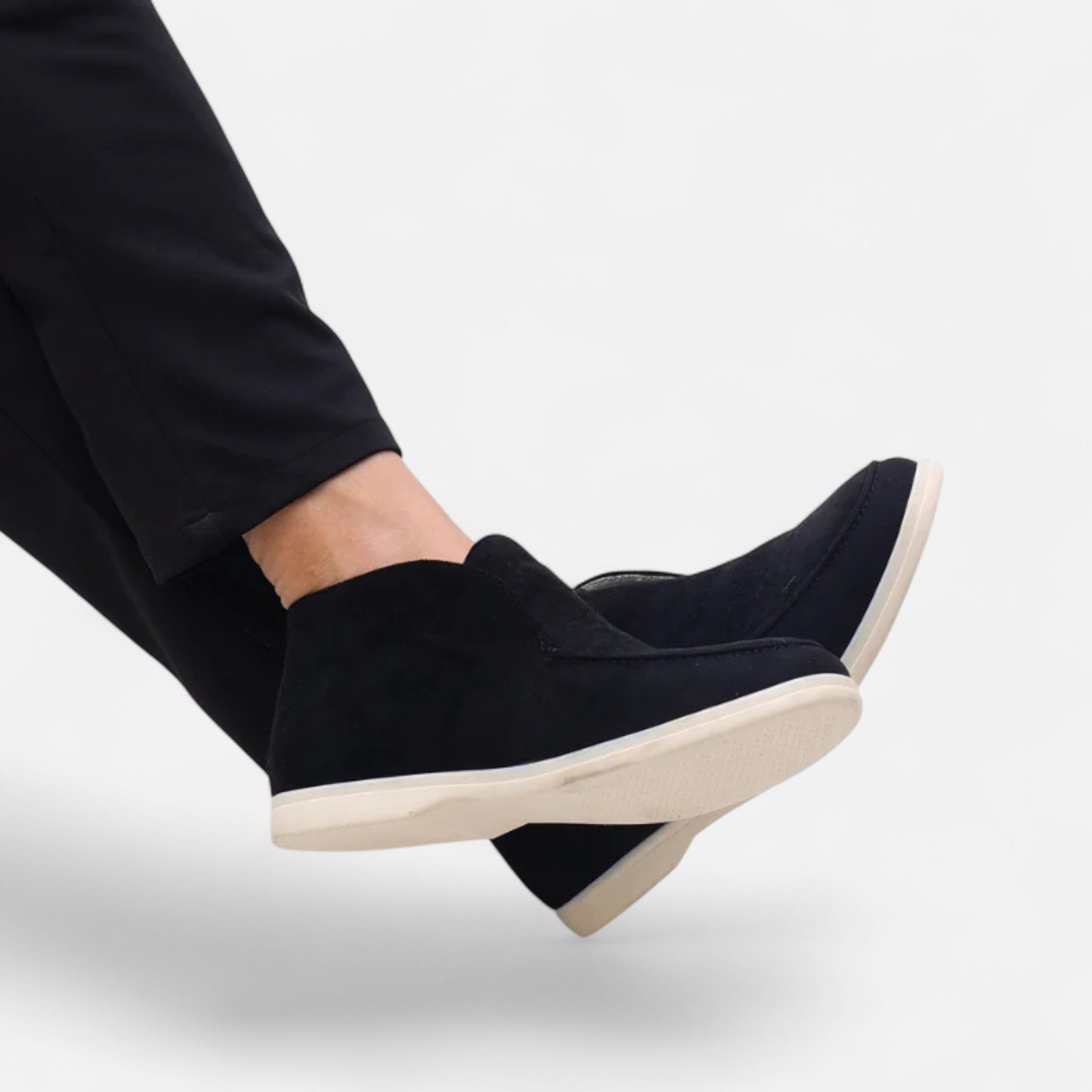 Black wedge shoes worn with black pants on a white background