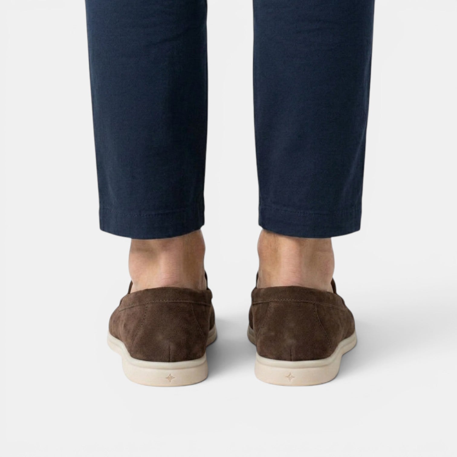 Brown suede shoes worn with navy pants on a white background