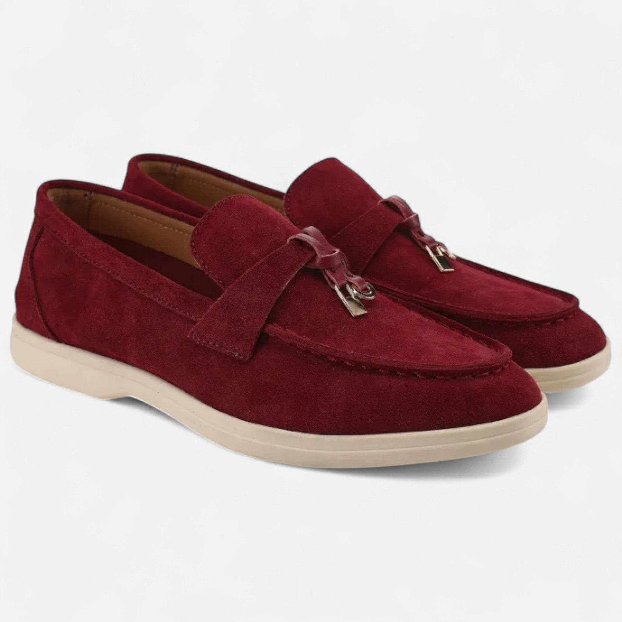 Pair of red loafers with a gold buckle on a white background