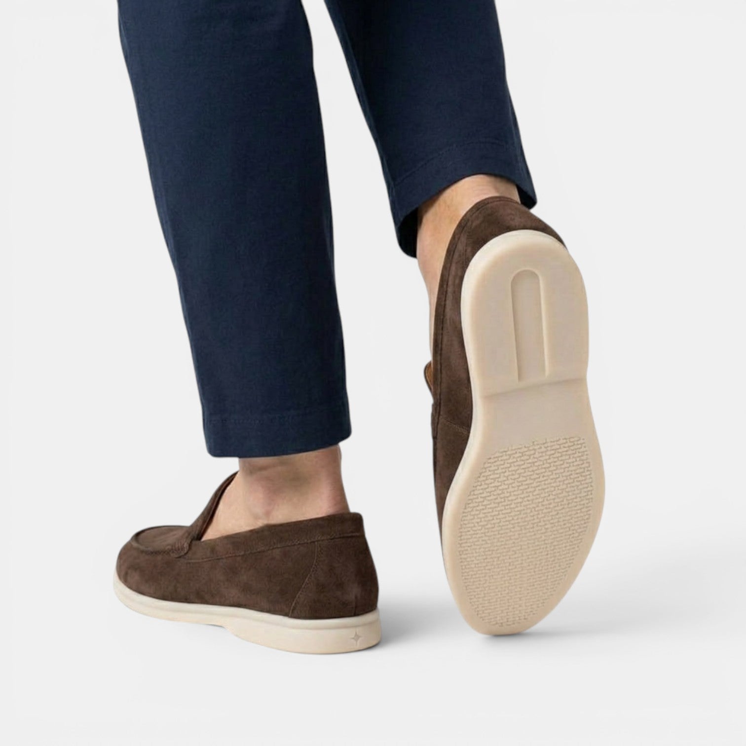 Brown loafers worn with navy pants on a light gray background
