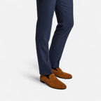 Navy blue dress pants with brown loafers on a light gray background