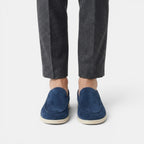 Navy loafers worn with gray pants on a white background
