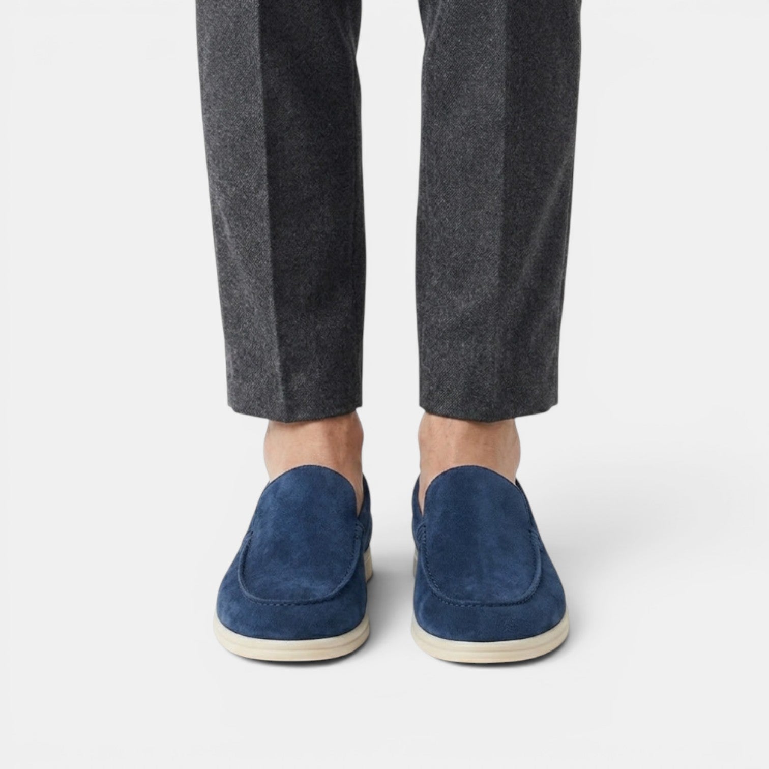 Navy loafers worn with gray pants on a white background