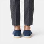 Person wearing dark blue espadrilles and gray pants on a white background
