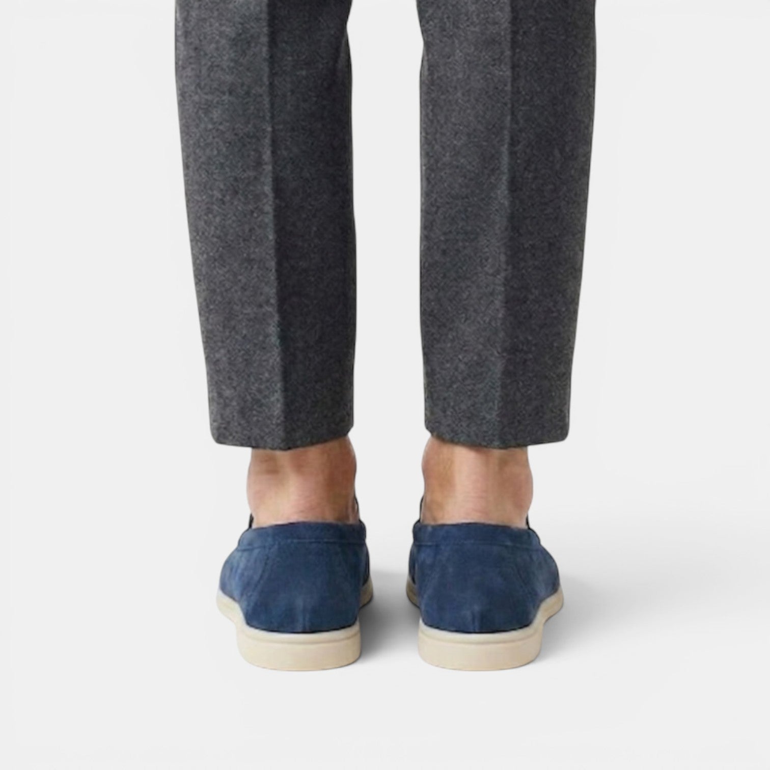 Person wearing dark blue espadrilles and gray pants on a white background