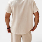 Man wearing a beige shirt and pants on a white background