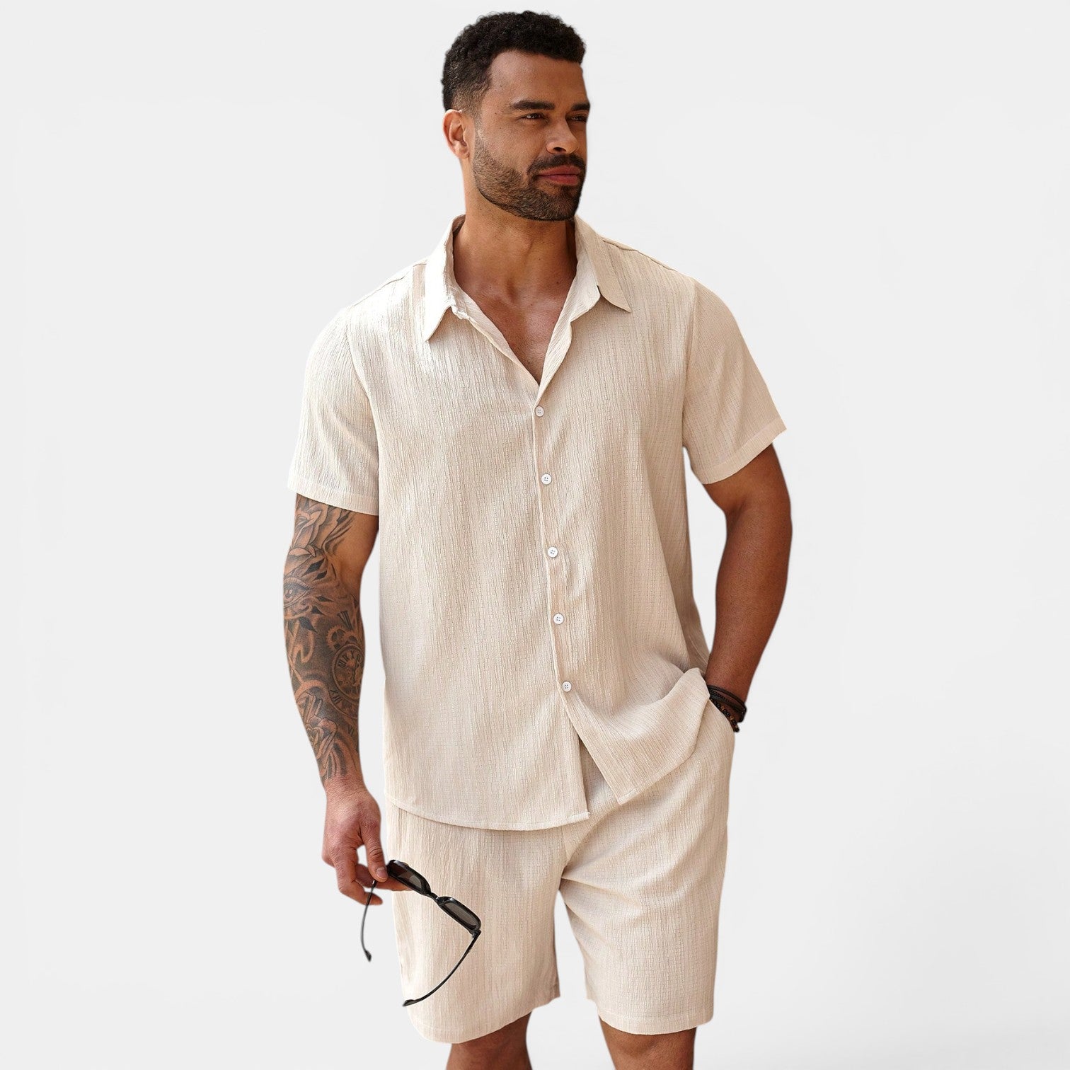 Man wearing a beige linen shirt and shorts set on a white background