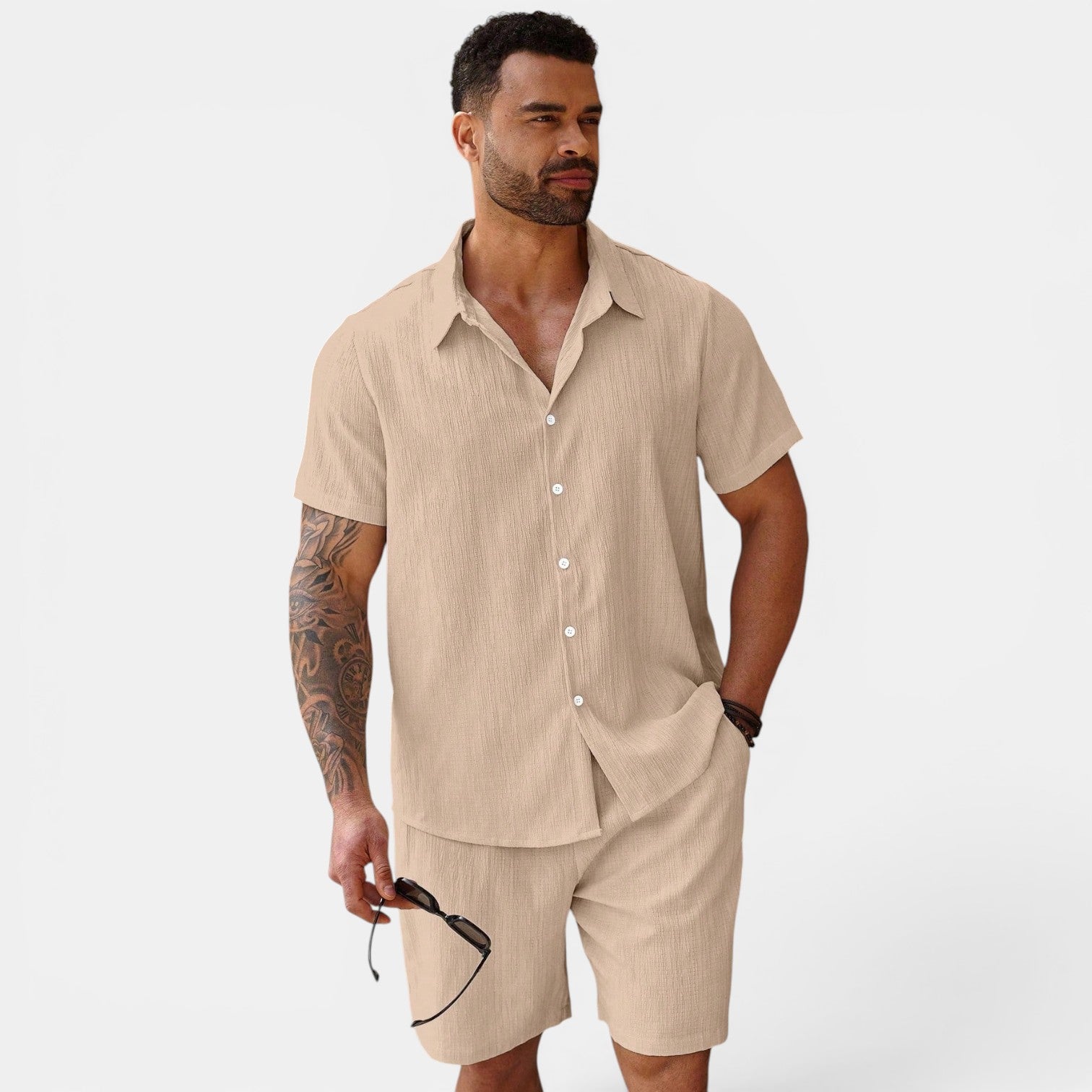 Man wearing a beige linen shirt and shorts set on a white background