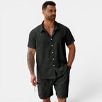 Man wearing a dark green button-up shirt and shorts on a white background