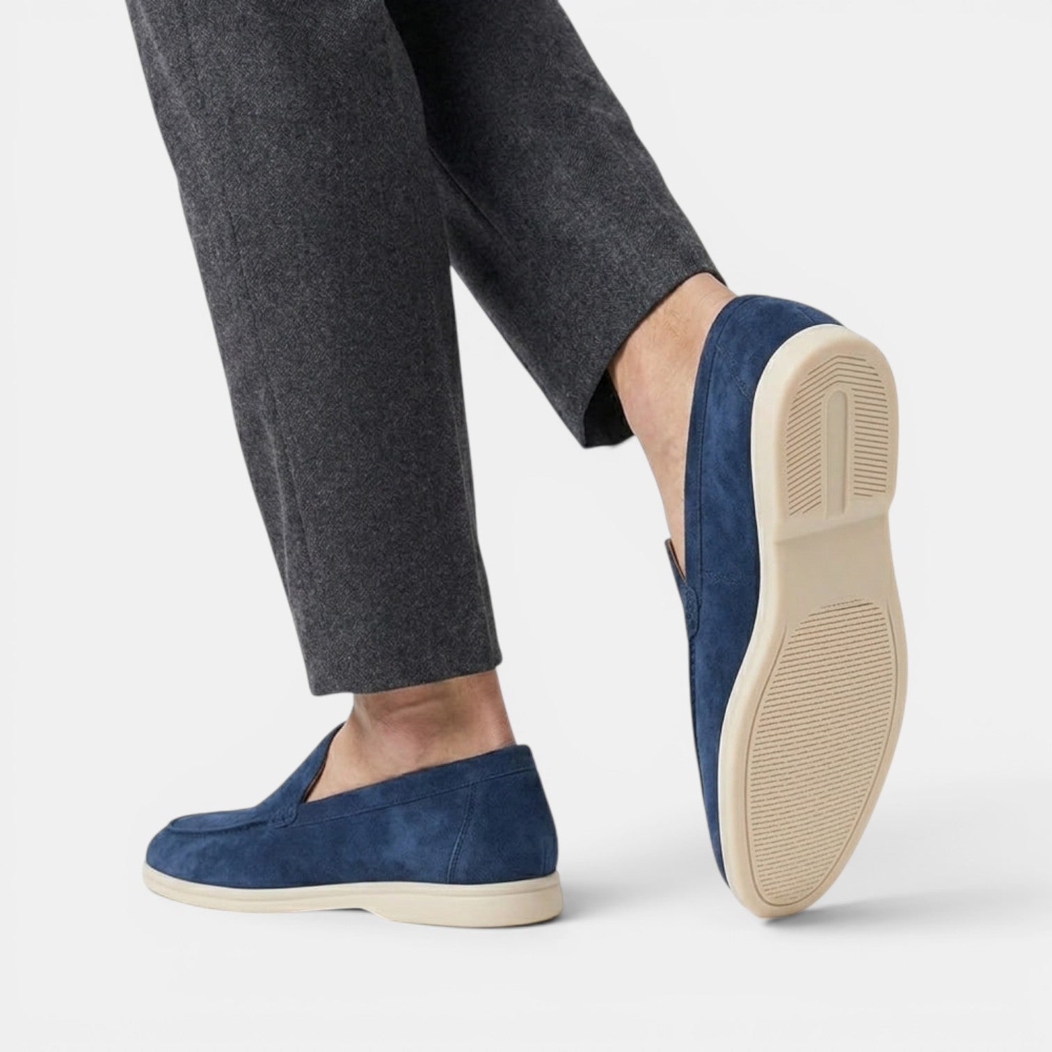 Navy loafers worn with gray pants on a white background