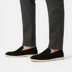 Black loafers worn with dark pants on a white background