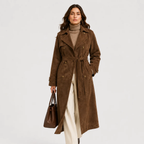 A woman models a brown suede longline trench coat over a beige turtleneck and cream wide-leg trousers, holding a matching brown leather handbag against a light gray studio background.