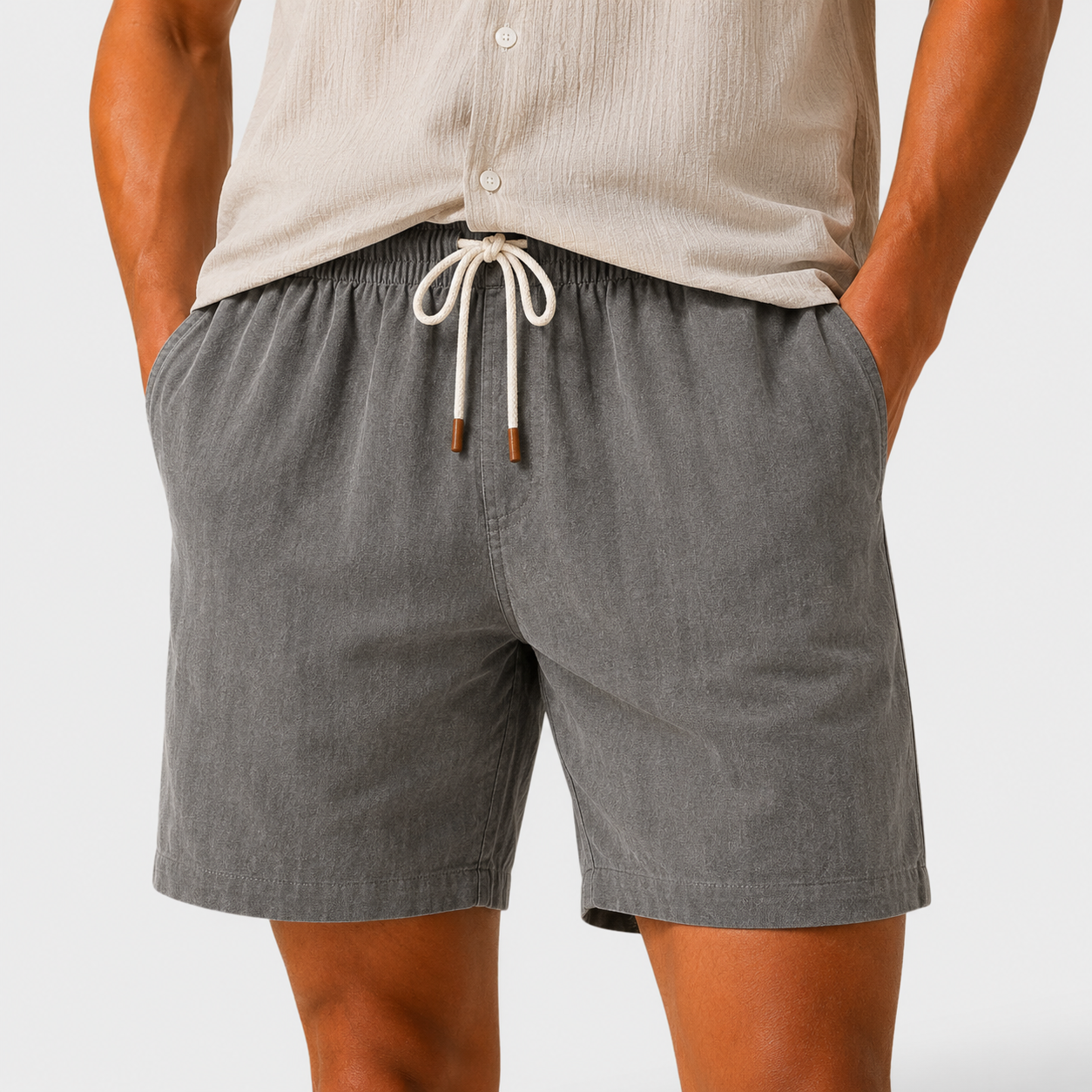 Person wearing gray shorts with a drawstring on a plain background