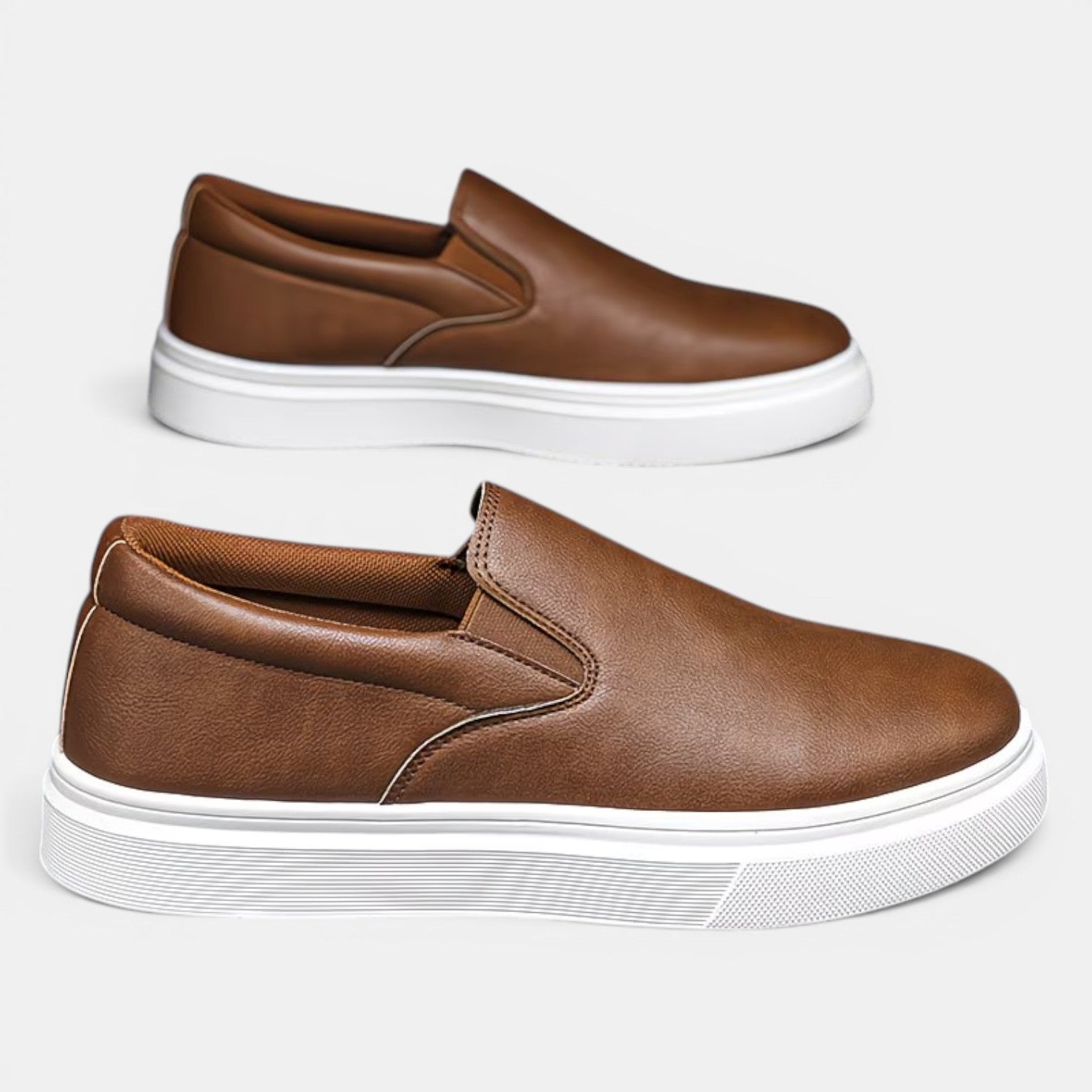 Pair of brown slip-on shoes with white soles on a light gray background