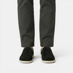 Person wearing black pants and black shoes on a white background