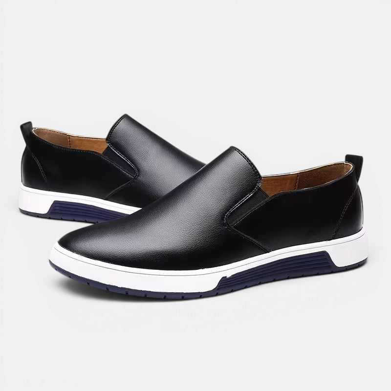 Black slip-on shoes with white soles on a light gray background