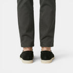 Person wearing dark green pants and black shoes on a white background