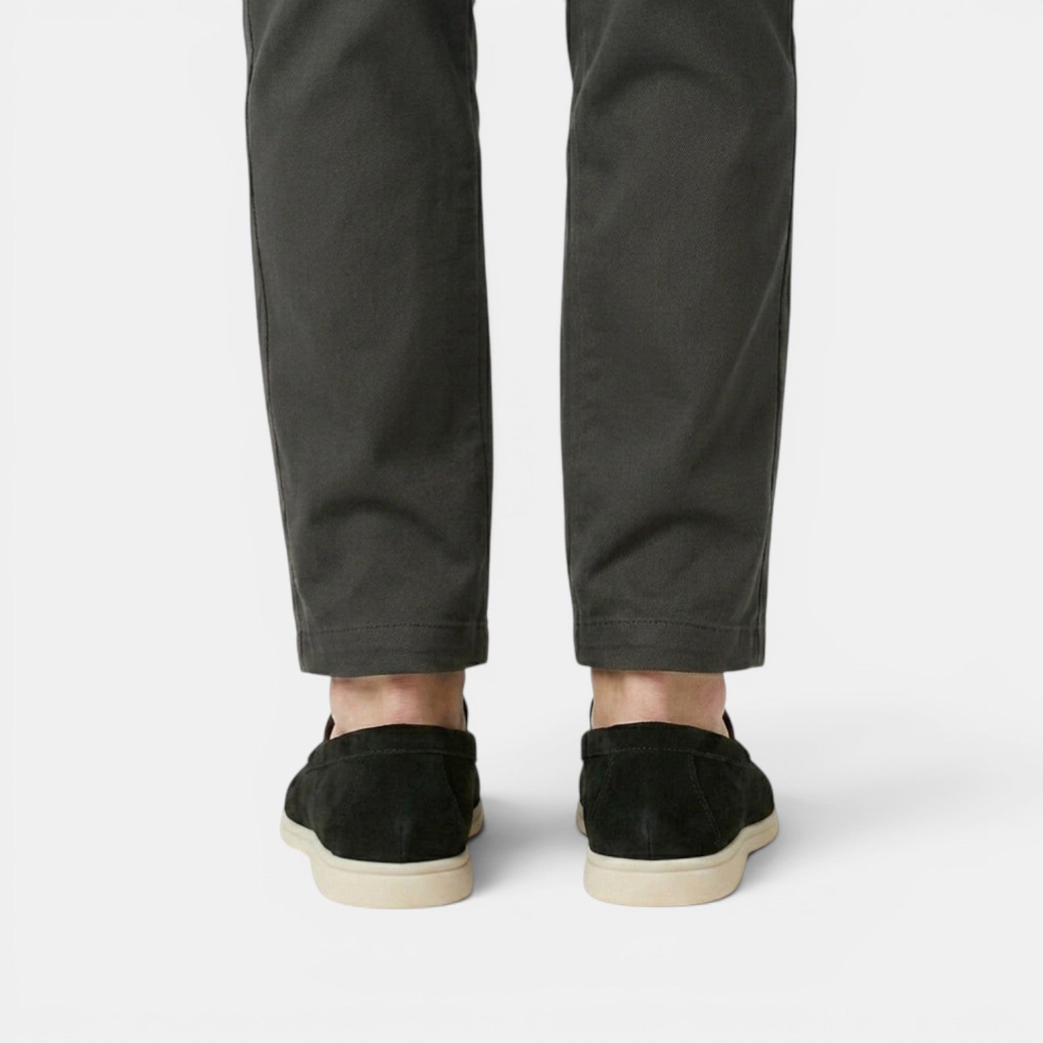 Person wearing dark green pants and black shoes on a white background