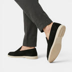 Black loafers worn with gray pants on a white background