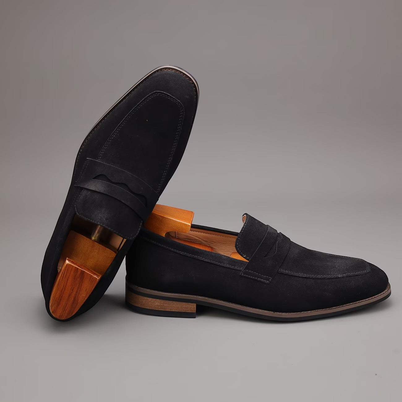 Pair of black loafers with wooden soles on a gray background