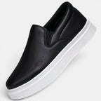Black slip-on sneaker with a white sole on a light gray background
