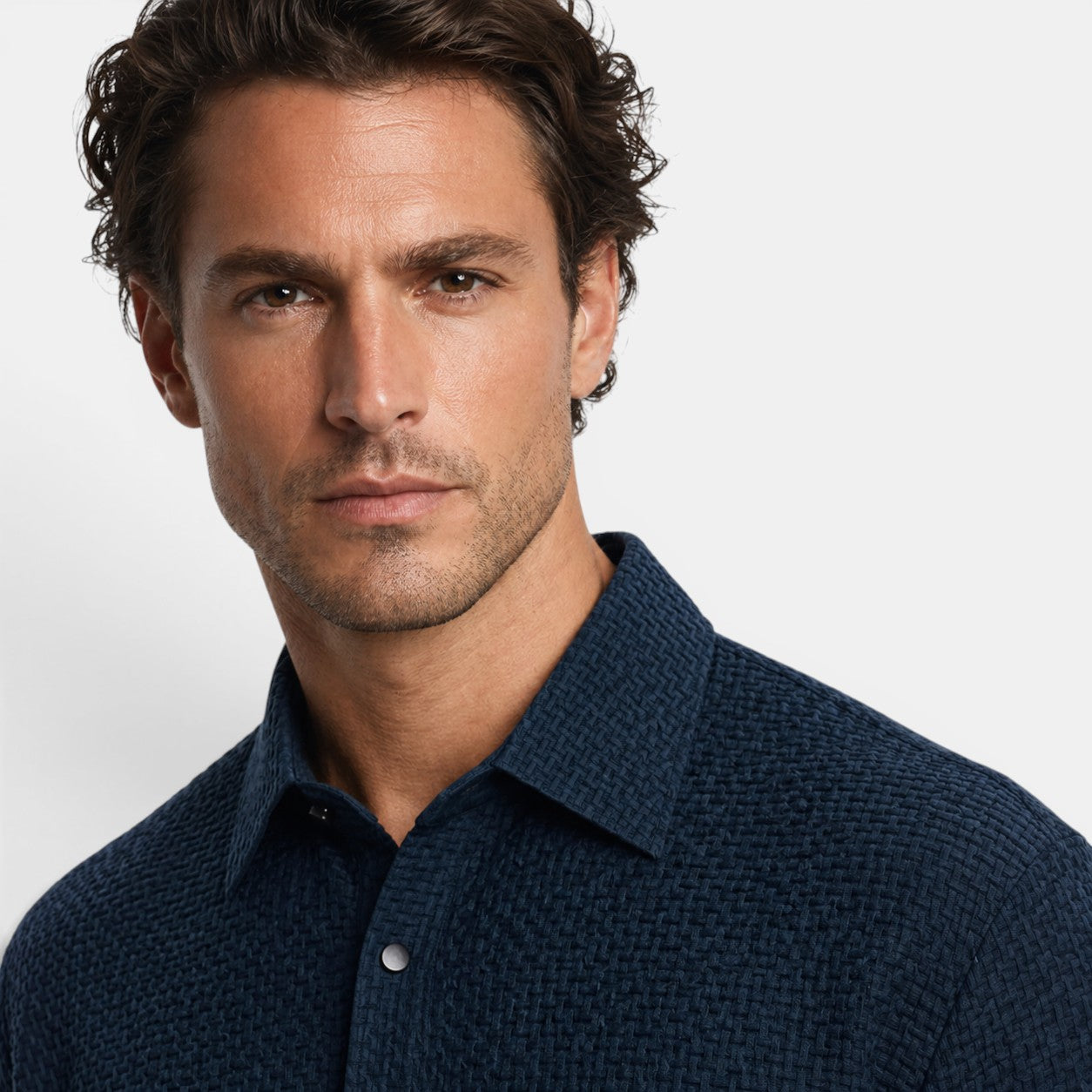 Man wearing a dark blue textured shirt against a plain background