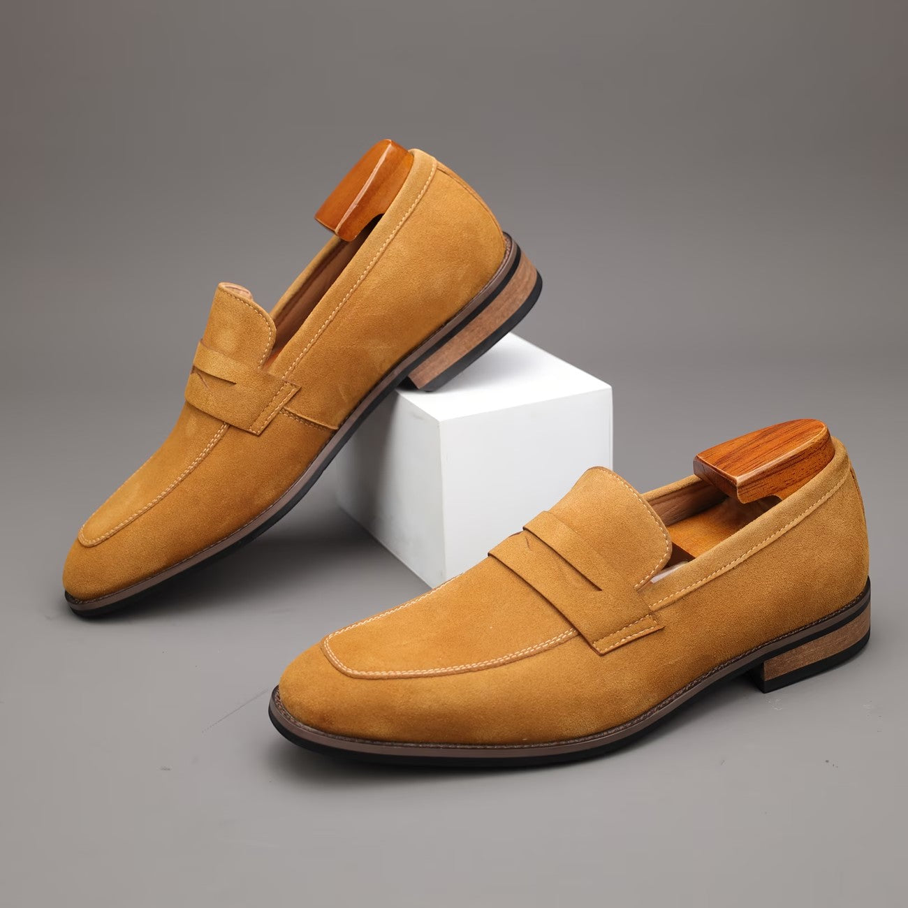Pair of tan loafers on a gray background