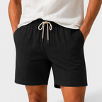 Person wearing black shorts with a white drawstring on a light gray background