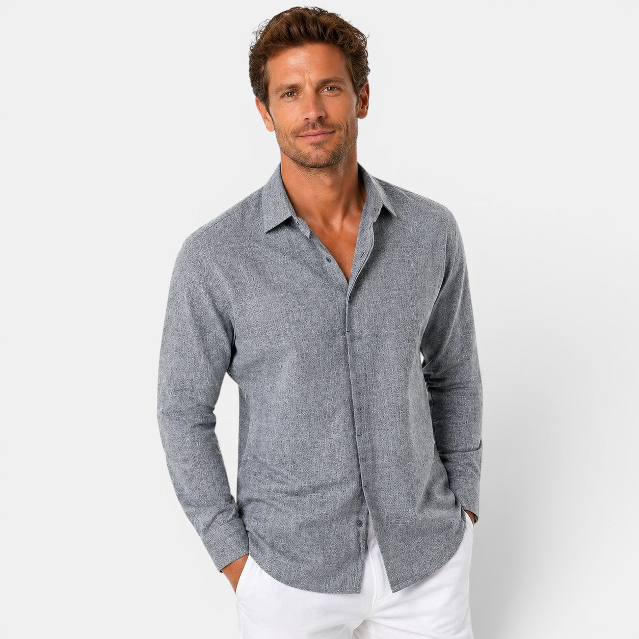 Man wearing a gray button-up shirt and white pants on a light gray background