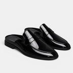 Black patent leather loafers on a light gray background