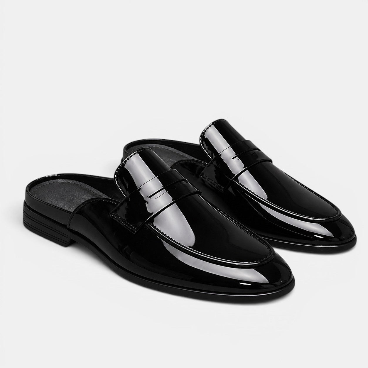 Black patent leather loafers on a light gray background