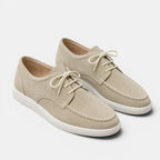 Pair of beige sneakers with white soles on a light gray background