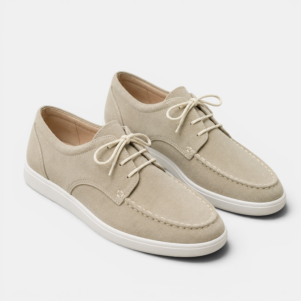 Pair of beige sneakers with white soles on a light gray background