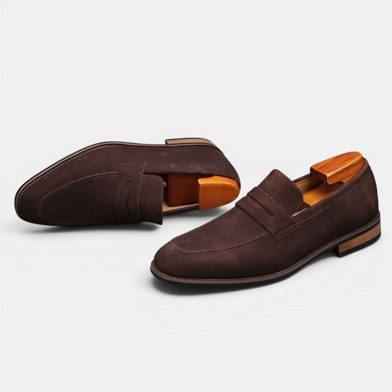 Pair of brown suede loafers on a light gray background