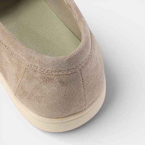 Close-up of a beige suede shoe on a light gray background