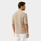 Man wearing a beige textured shirt and white pants on a light gray background