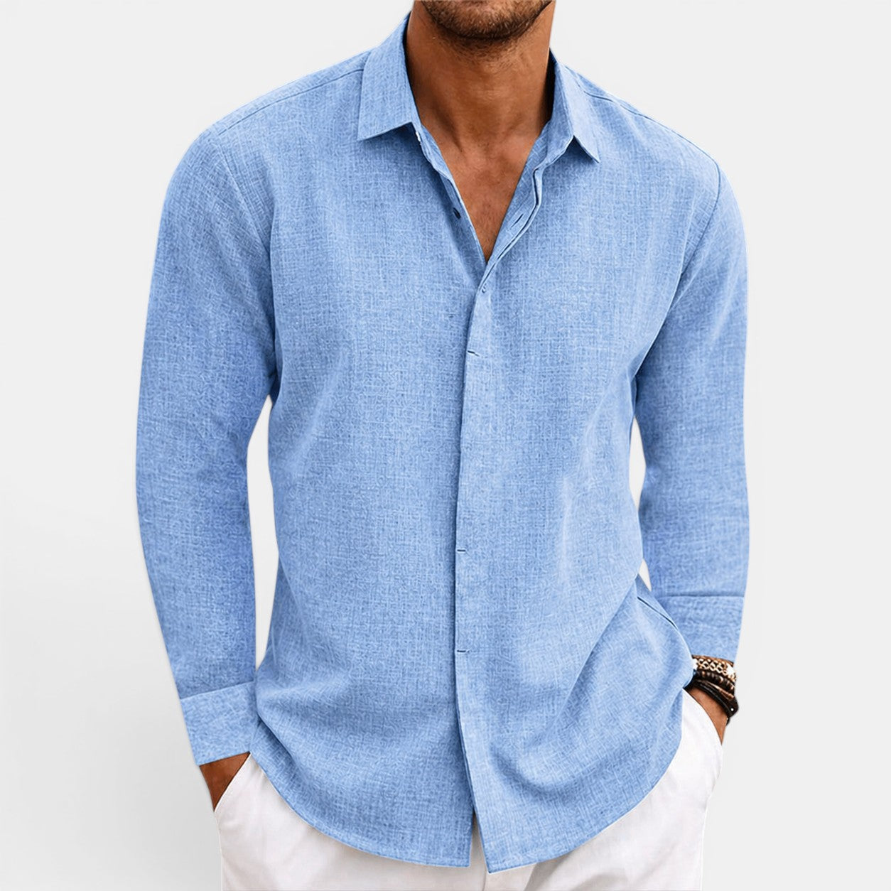 Man wearing a light blue button-up shirt with rolled-up sleeves on a white background