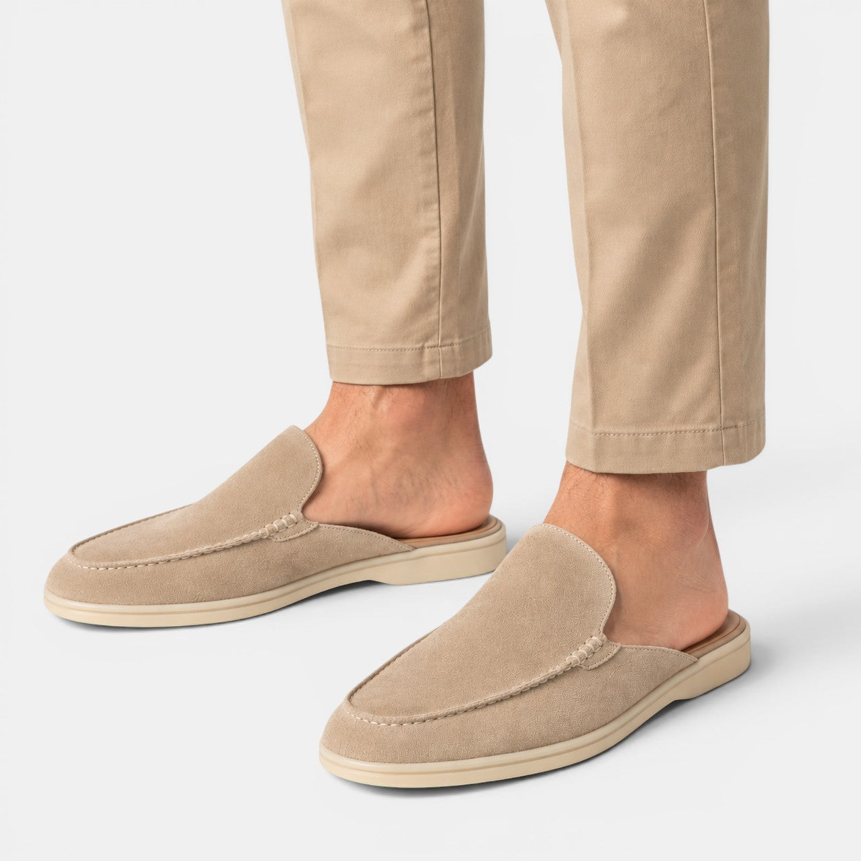Beige slippers worn with beige pants on a light gray background