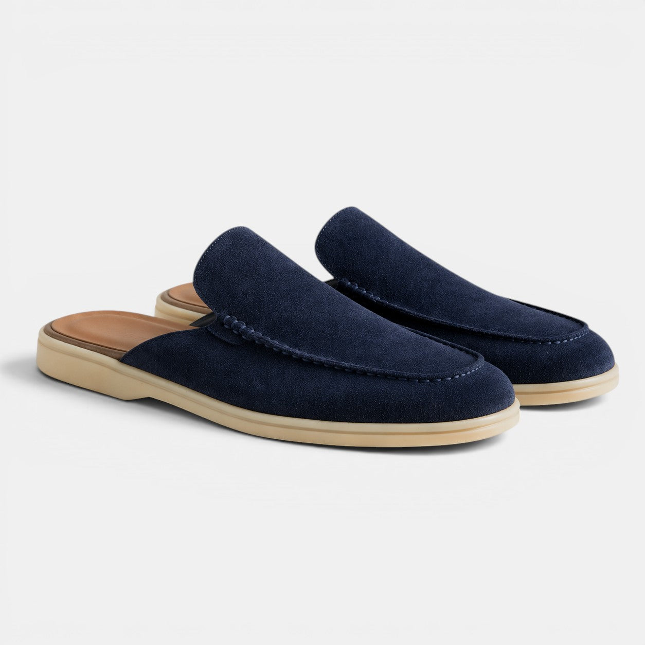 Pair of navy blue slippers with beige soles on a light gray background