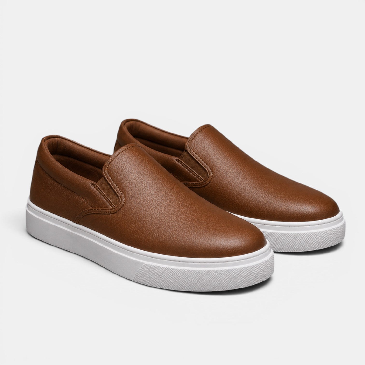 Brown slip-on sneakers with white soles on a light gray background