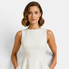 Woman wearing a white sleeveless dress against a plain background