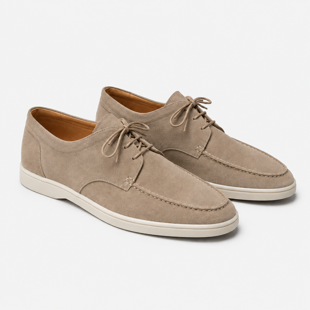 A pair of taupe suede boat shoes with cream-colored soles, displayed on a clean light gray background.