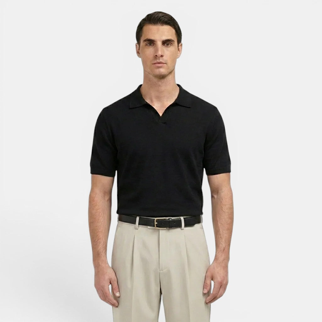 Man wearing a black polo shirt and beige pants on a white background