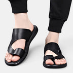 Black sandals worn with black pants on a light gray background