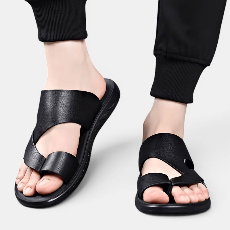 Black sandals worn with black pants on a light gray background